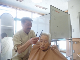 スタッフが入居者のヘアカットを行っている様子