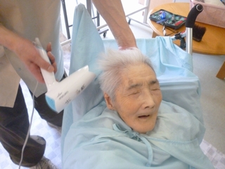 スタッフが入居者の頭部に冷たいタオルを当てている様子。介護・ケアの場面